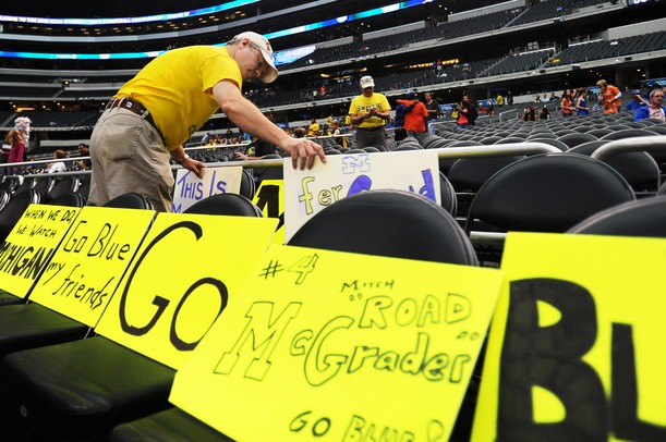 Michigan fan Gary Myers, of Denver, Colorado, distributes the signs he made over two rows of seats before the start of Michigan's Elite Eight game against Florida at Cowboys Stadium on Sunday, March 31, 2013. Melanie Maxwell I AnnArbor.com